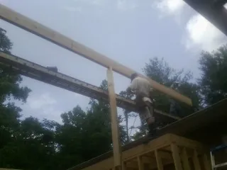 Carpenter setting a ridge beam over a new addition frame — Ice Dam Removal by Roofing Brothers in Tomkins Cove