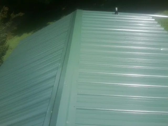 New green metal panels meeting at the ridge of a roof — Flat Roof Repair work by our crew in Tomkins Cove