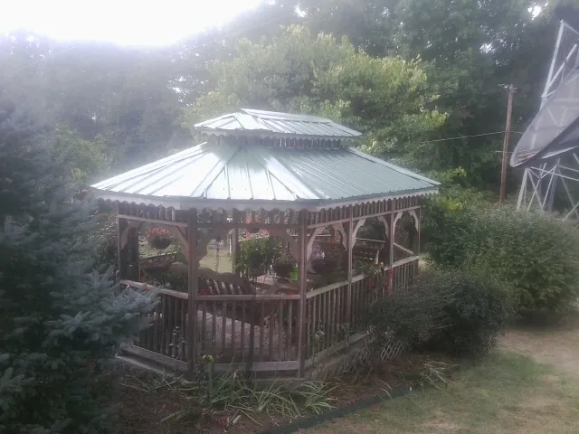 Green metal roof on a backyard gazebo surrounded by garden beds in Tomkins Cove