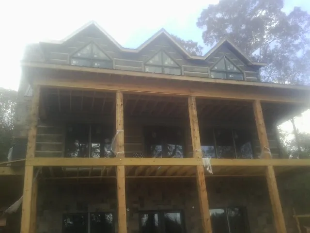 Dormers and porch framing on a large log home under construction — Roof Coating work by our crew in Tomkins Cove