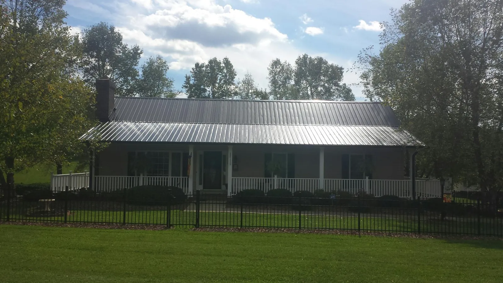 Gray metal roof on a brick ranch with a full width front porch — Gutter Guard Installation work by our crew in Tomkins Cove