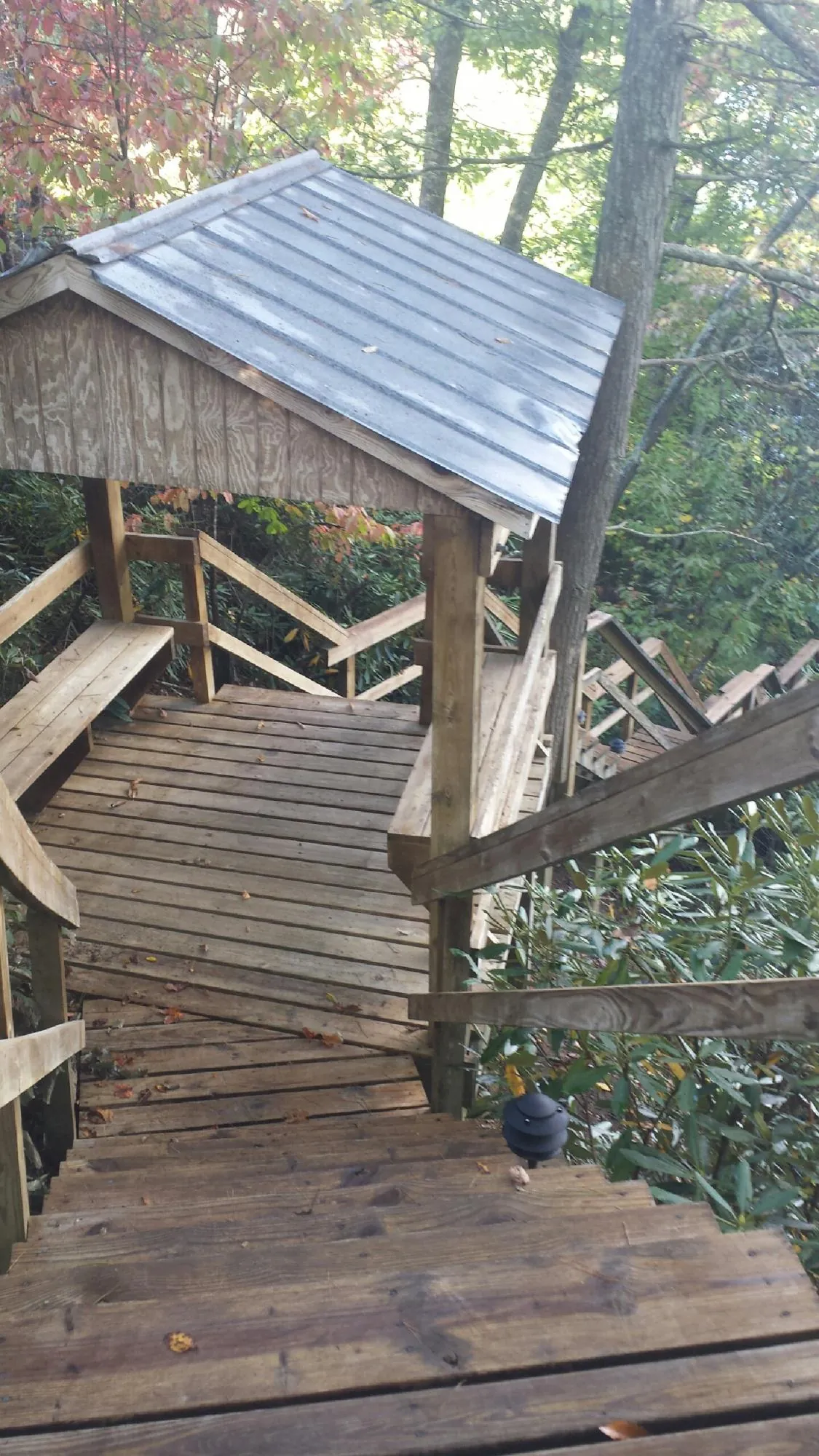 Metal roofed shelter over wooden steps on a wooded walkway — Skylight Repair & Installation work by our crew in Tomkins Cove