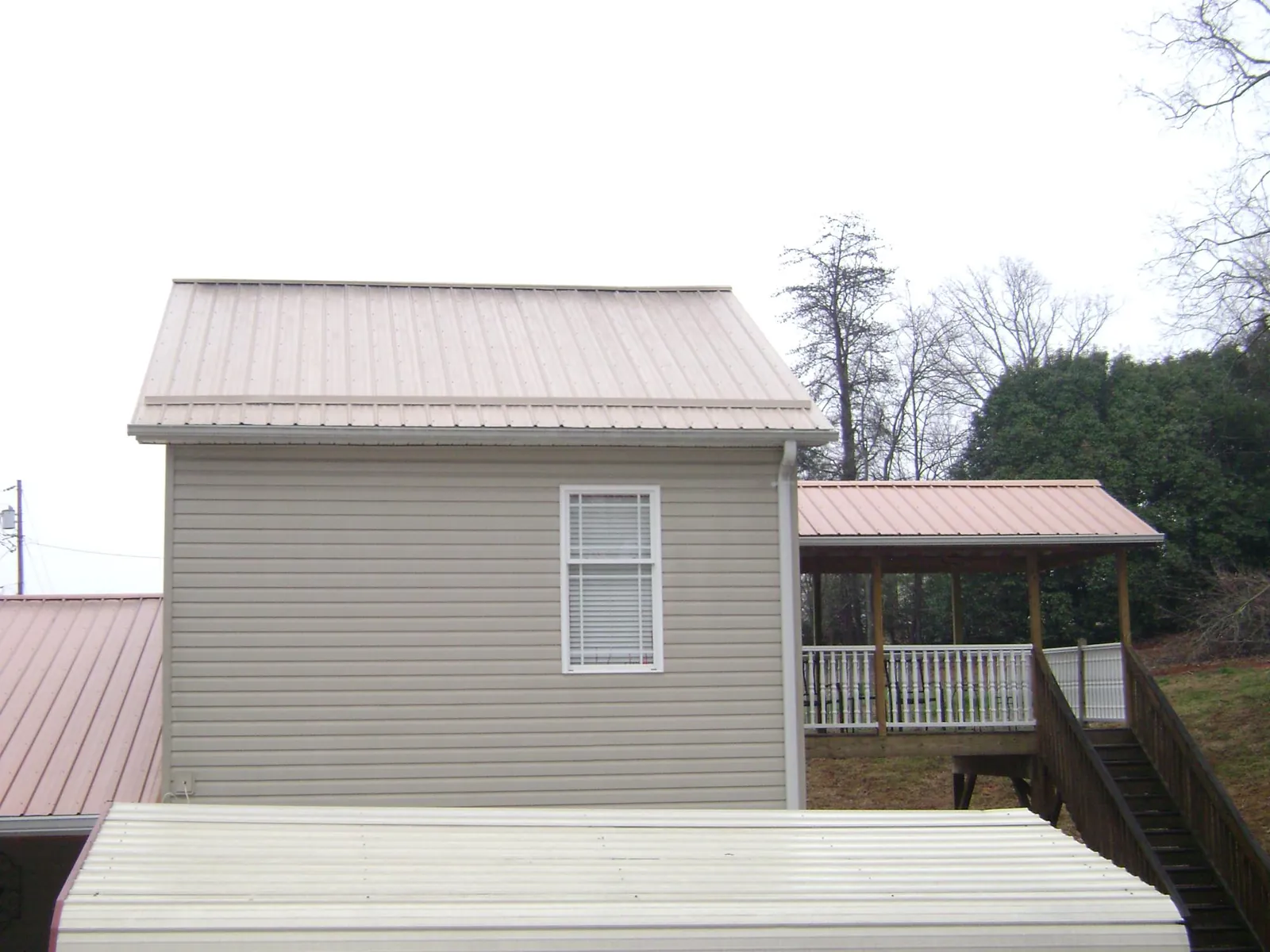 Tan metal roofs on a two story addition and attached porch, from a Roof Replacement job in Tomkins Cove