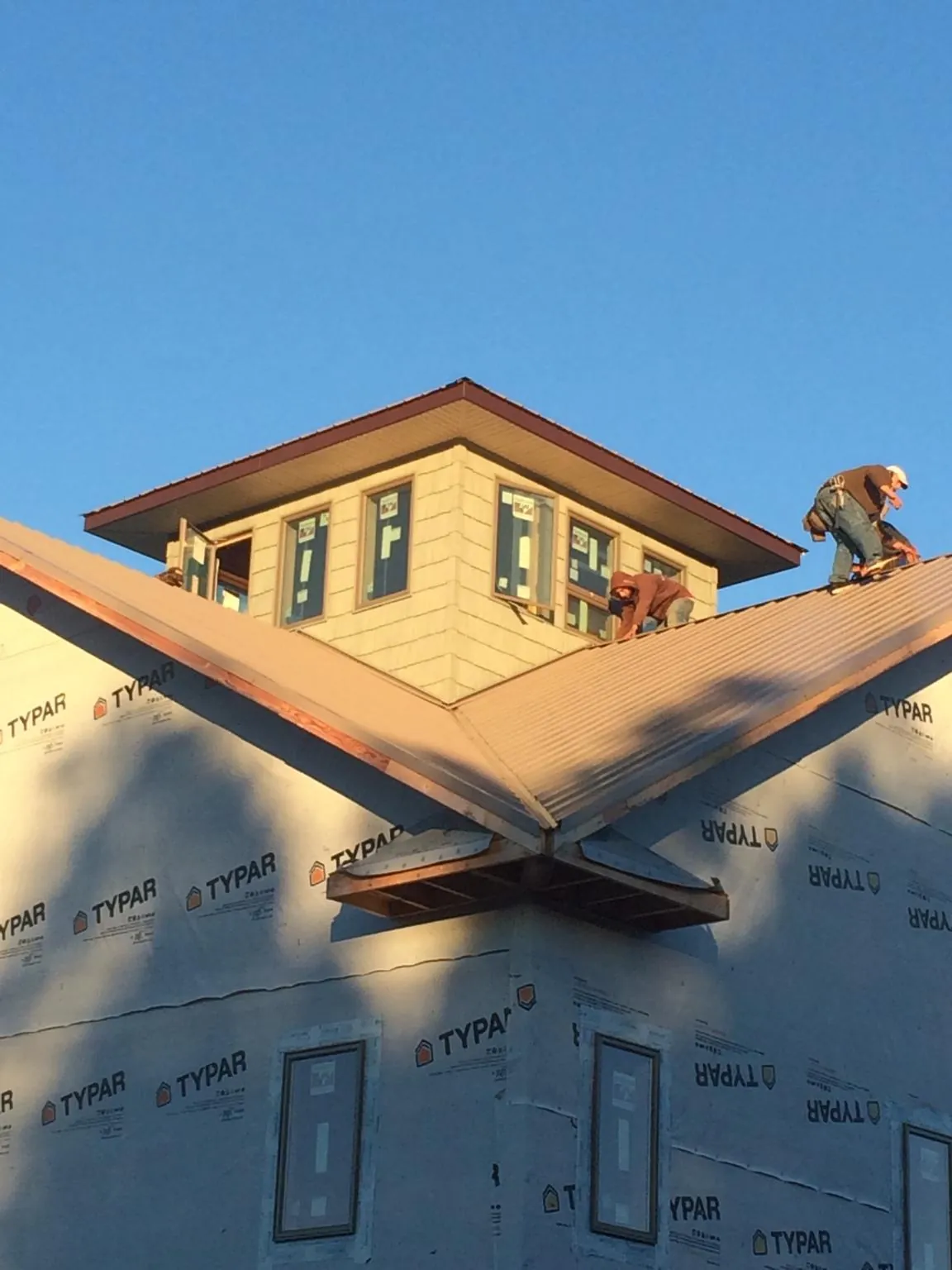 Roofers working around a rooftop cupola on a new metal roof at sunset — Roof Waterproofing in Tomkins Cove by Roofing Brothers